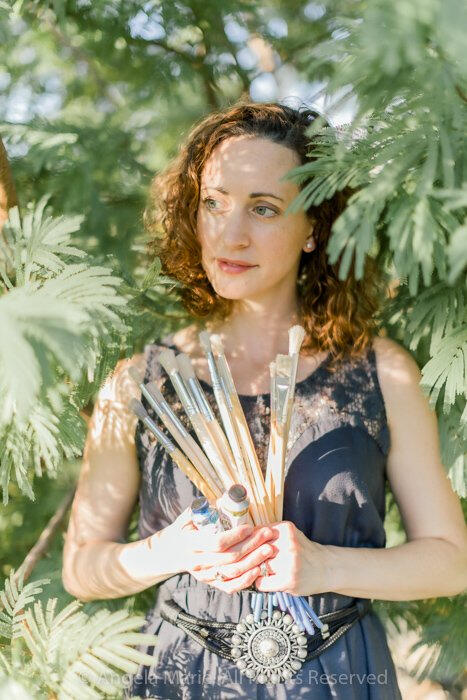 The artist, Angela Marie pictured with brushes and paint.